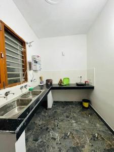 a kitchen with two sinks and a black counter top at Chanchal Niwas in Kharar