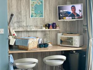 a kitchen with a counter with a microwave and two stools at Seaside Homestay - Ensuite twin room with Kitchenette in Paignton