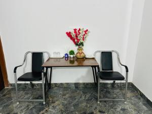 a dining room table with two chairs and a vase with flowers at Chanchal Niwas in Kharar