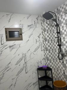 a shower in a bathroom with a white marble wall at شقة تتوفر على جميع شروط الراحة و الامان in Benguerir