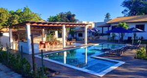 a swimming pool with a pergola next to a house at Pousada Aquarela De Imbassaí in Imbassai