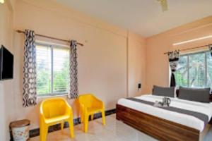 Thākurdwari的住宿－Arhan Villa Inn Kolkata，一间卧室配有一张床和两张黄色椅子
