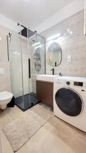 een badkamer met een douche en een wasmachine bij Moonshine Érd in Érd