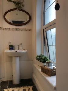 a bathroom with a sink and a mirror and a window at The Brick House, cosy cottage in North Cornwall in Saint Teath