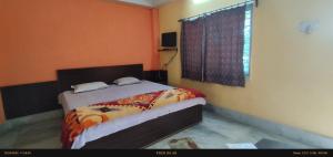 a bedroom with a bed with orange walls and a window at India Tours only Ekanta Apan in Mathurakhanga