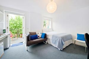 a white bedroom with a bed and a chair at Zone 1! 2 bed duplex Apartment! in London