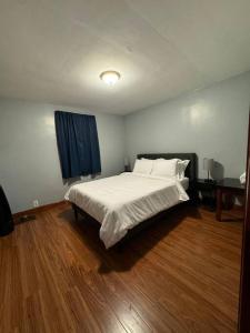 a bedroom with a white bed and a wooden floor at Comfy getaway at falls! in Niagara Falls