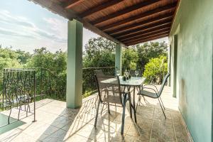 a patio with a table and chairs on a balcony at Armonia Holiday Home Corfu with King size Bed and Private Garden in Áyios Pandeleḯmon