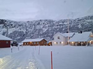 a snow covered town with houses and a mountain at Flott leilighet midt blant Lyngsalpene! in Lyngseidet