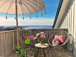 2 sillas con almohadas en un balcón con sombrilla en Lysekil sunset Villa en Lysekil