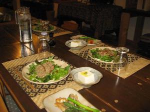 una mesa de madera con platos de comida. en Toipirka Kitaobihiro Youth Hostel, en Otofuke