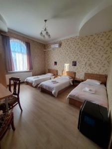 Zimmer mit 3 Betten, Tisch und Stühlen in der Unterkunft Gogi's Paradise Guesthouse in Akhmety