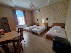 a hotel room with three beds and a table at Gogi's Paradise Guesthouse in Akhmety