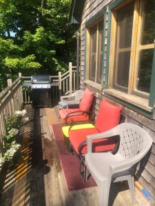 a porch with chairs and tables and a grill at Rustic Lakefront Cottage Derby Paddles Lodge in Derby Center +9 photos