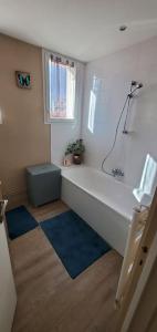 a bathroom with a white tub and blue rugs at Simplicité et calme en appartement à Issoire in Issoire