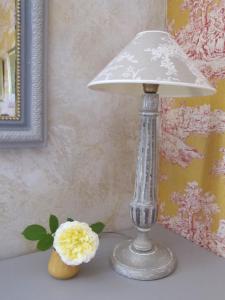 una lámpara sentada en una mesa junto a una flor en Le Mas des Clots, en Upie