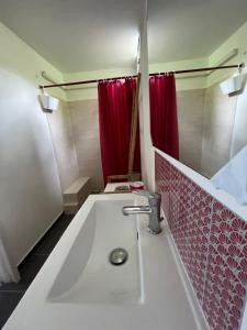 a bathroom with a sink and a red shower curtain at Eden Créole in Trois-Rivières