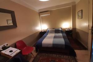 ein Hotelzimmer mit einem Bett und einem roten Stuhl in der Unterkunft Flat with private parking, in the heart of Sete in Sète