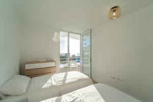 a white bedroom with two beds and a balcony at Moderní vila s bazénem in Adeje