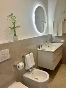 ein Badezimmer mit einem Waschbecken, einem WC und einem Spiegel in der Unterkunft Alchimia Apartment in Conversano