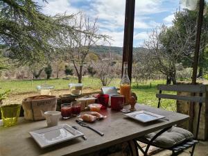 a picnic table with food and a bottle of wine at La ferme d'Andréa au milieu des vignes à 3min à pied du centre piscine chauffée climatisation in Lourmarin
