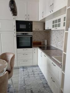 a kitchen with white cabinets and a stove top oven at Apartmani Dar Lux in Banja Koviljača