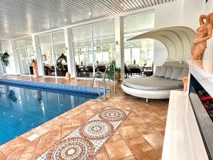 a swimming pool with a bed and a couch in a house at Ringhotel Siegfriedbrunnen in Grasellenbach