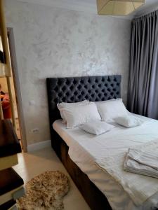 1 dormitorio con 1 cama con cabecero negro y almohadas blancas en Apartament Eva en Bacău