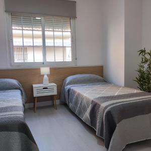 1 Schlafzimmer mit 2 Einzelbetten und einem Fenster in der Unterkunft Apartamentos Costa II in Los Alcázares