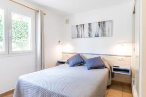 biała sypialnia z łóżkiem z 2 niebieskimi poduszkami w obiekcie Villa ES MIRADOR w Son Bou +22 zdjęcia