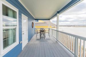 a balcony with tables and chairs on a blue house at Waterfront Seabrook Amazing View Kingbed in Seabrook