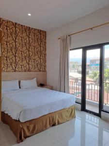 a bedroom with a bed and a large window at BahuBay Hotel Manado in Malalayang