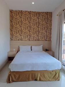 a bedroom with a large white bed with a wall at BahuBay Hotel Manado in Malalayang