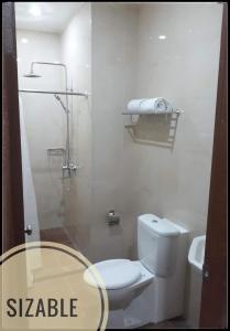 a bathroom with a white toilet and a shower at BahuBay Hotel Manado in Malalayang