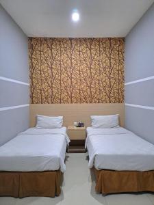 two beds in a room with a wall mural at BahuBay Hotel Manado in Malalayang