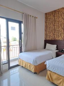 a hotel room with two beds and a window at BahuBay Hotel Manado in Malalayang