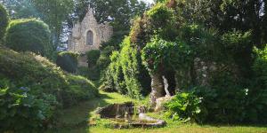 eine Kirche inmitten eines Gartens mit einem Bach in der Unterkunft LE POINT DU JOUR in Saint-Savin
