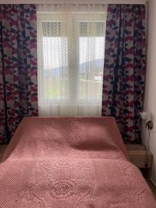 um quarto com uma cama rosa e uma janela em Apartmani Urošević em Vrhpolje