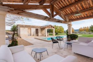 un patio con muebles blancos y una piscina en Luxury provencal farmhouse - Mas de l'Estel, en Cucuron