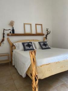 una camera con letto in legno e 2 cuscini di I Ginepri a Teulada