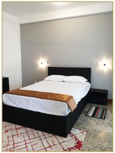 um quarto com uma cama grande e lençóis brancos em Orange Guest Homes & Banquet Hall em Serukele