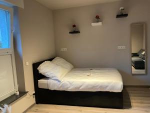 a small bedroom with a bed with white sheets at Modernes Studio am Dreiländereck in Alsdorf