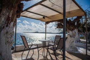 a table and chairs on a patio with a view of the water at Zafeiropoulos Apartments in Marathopoli