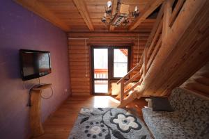 a living room with a tv and stairs in a cabin at Приватна садиба Дикий Мед in Ploskoye