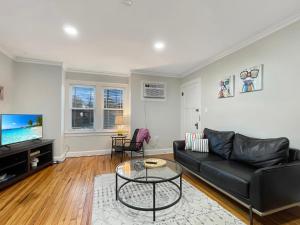 uma sala de estar com um sofá preto e uma televisão em Fun & Charming 1br Apt Near Drake em Des Moines