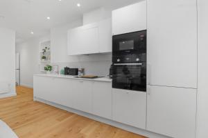 a white kitchen with white cabinets and a microwave at City Escape with a Touch of Class in Eastbourne