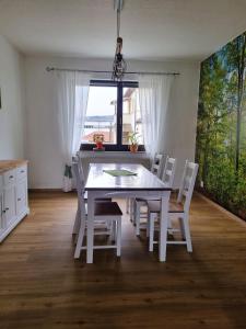 mesa de comedor blanca con sillas blancas y ventana en Ferienwohnung Cumbach, en Rudolstadt