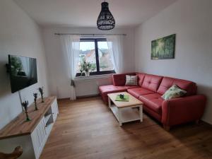 a living room with a red couch and a table at Ferienwohnung Cumbach in Rudolstadt
