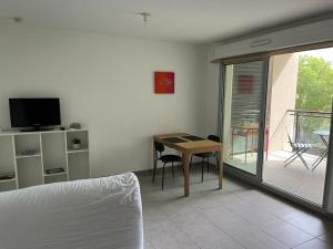 Cette chambre comprend un lit, une table et un balcon. dans l'établissement Joli T2 avec terrasse au calme, à Montpellier
