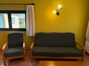 2 Stühle in einem Zimmer mit gelber Wand in der Unterkunft Can Pujol - Turismo Rural in Serra de Daró